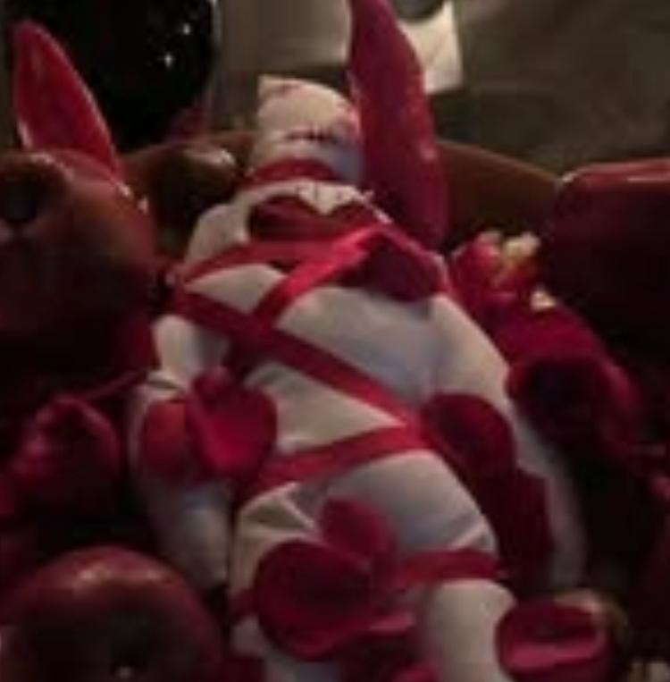 Simbolismo em tecido branco com fitas vermelhas e pétalas.